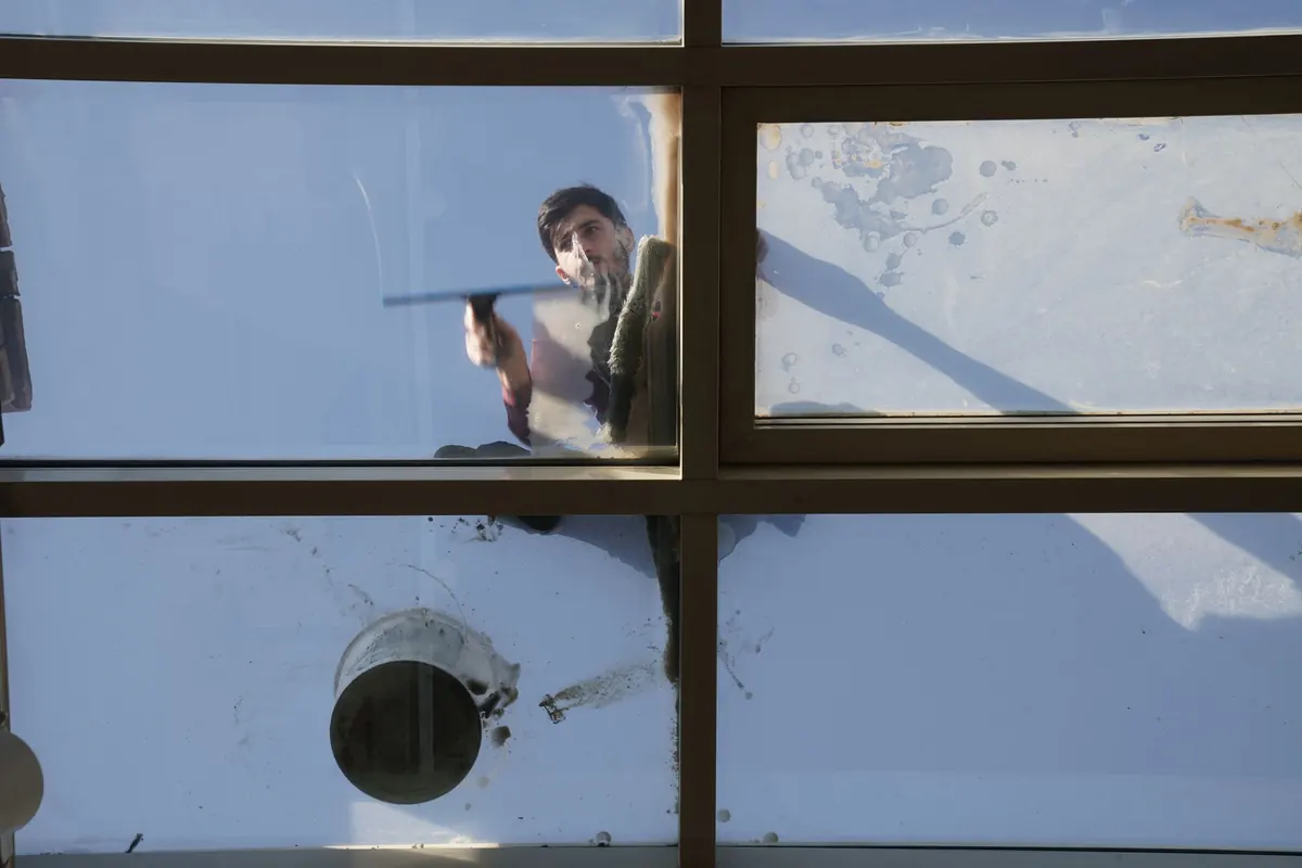 A window cleaner squeegeeing the outside of a divided window, seen from indoors