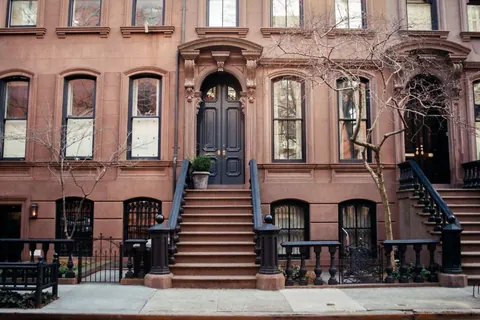 A row of Brooklyn brownstones with stoops and tall windows along a tree-lined street