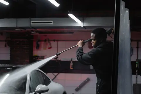 A worker pressure-washing a surface with a high-pressure spray wand