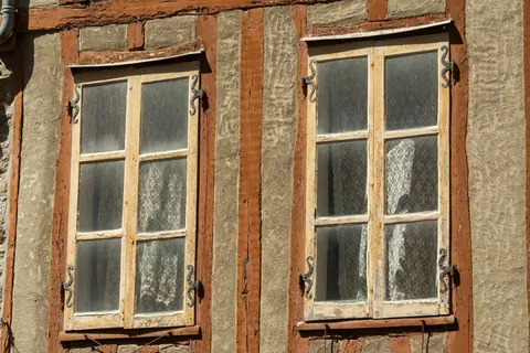Two old wooden casement windows set in a weathered wall