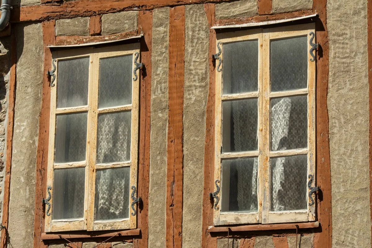 Two old wooden casement windows set in a weathered wall