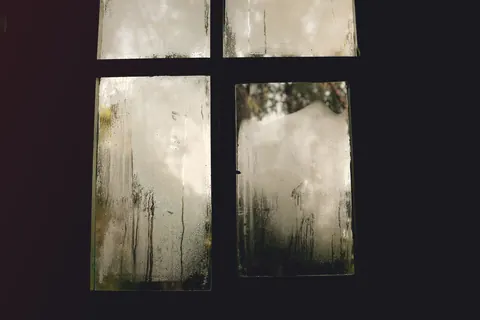 A window heavily fogged with internal condensation from a failed insulating seal