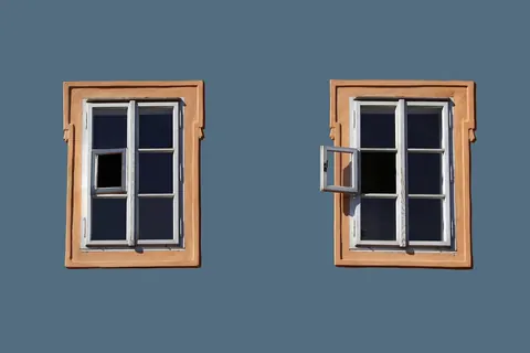 Framed residential windows on an exterior wall, showing different glass and frame types