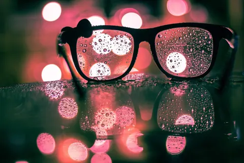 Hard-water droplets and mineral spots drying on a pane of glass