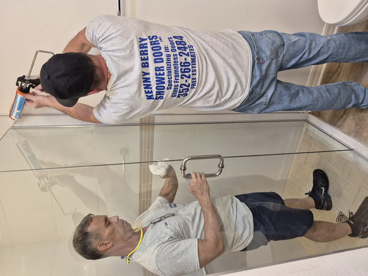 A glass shower door panel being fitted into its frame during installation