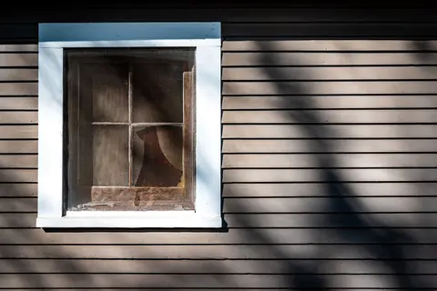 Hard afternoon sun throwing sharp shadows across a window and lap siding