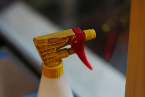 Close-up of a yellow spray-bottle trigger used for window cleaning solution