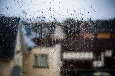 Raindrops on a window with houses blurred beyond