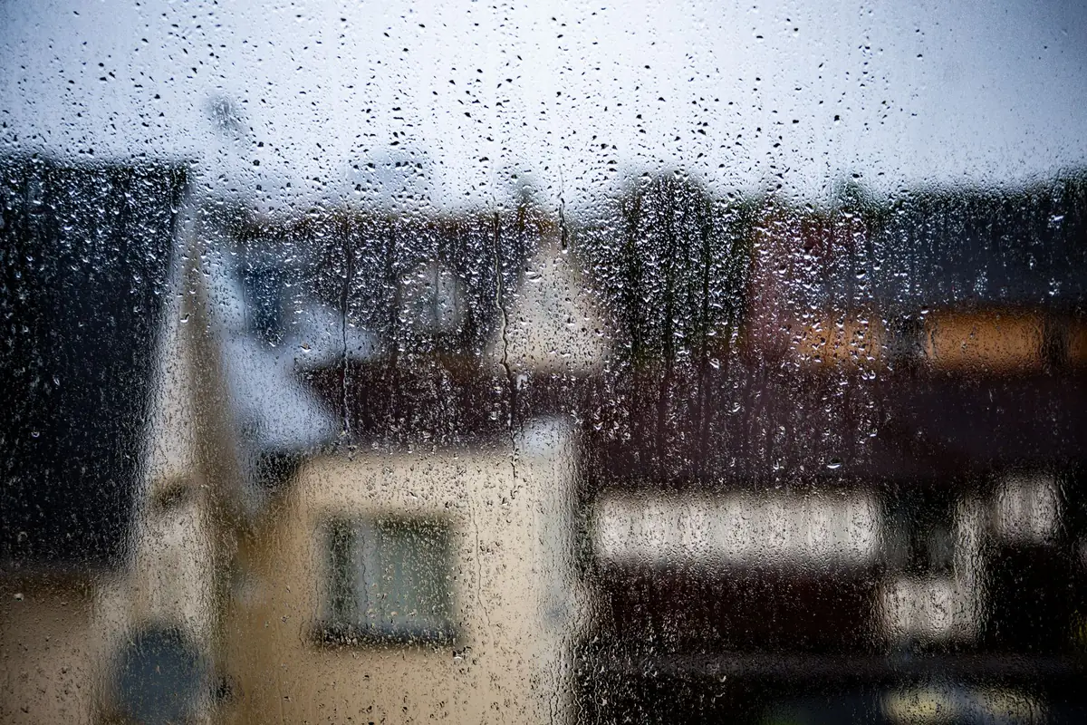 Raindrops on a window with houses blurred beyond