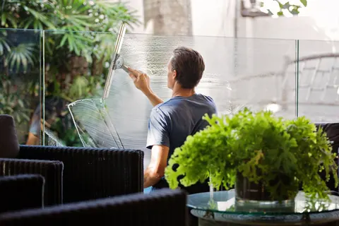 A man drawing a squeegee across a tall glass panel