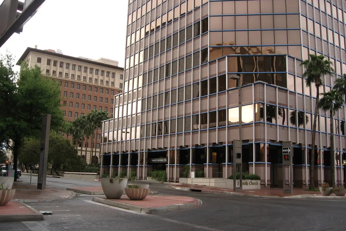 A bronze-glass office tower on a palm-lined street in downtown Tucson