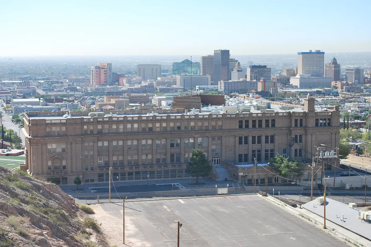 El Paso High School's columned front, with downtown El Paso's towers on the skyline behind it