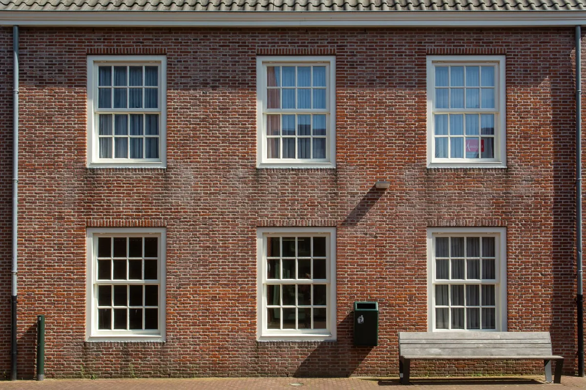 A brick building with rows of white sash windows