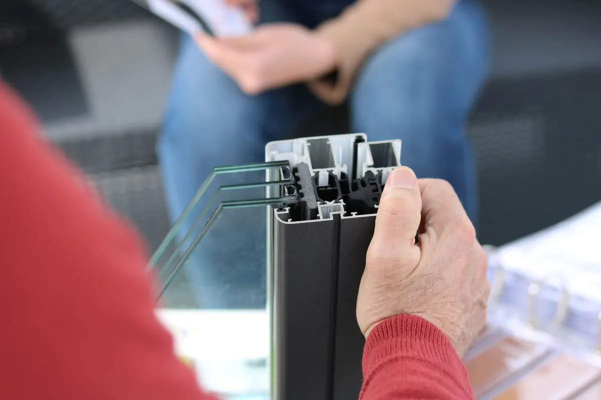 A hand holding a cut sample of a window frame profile