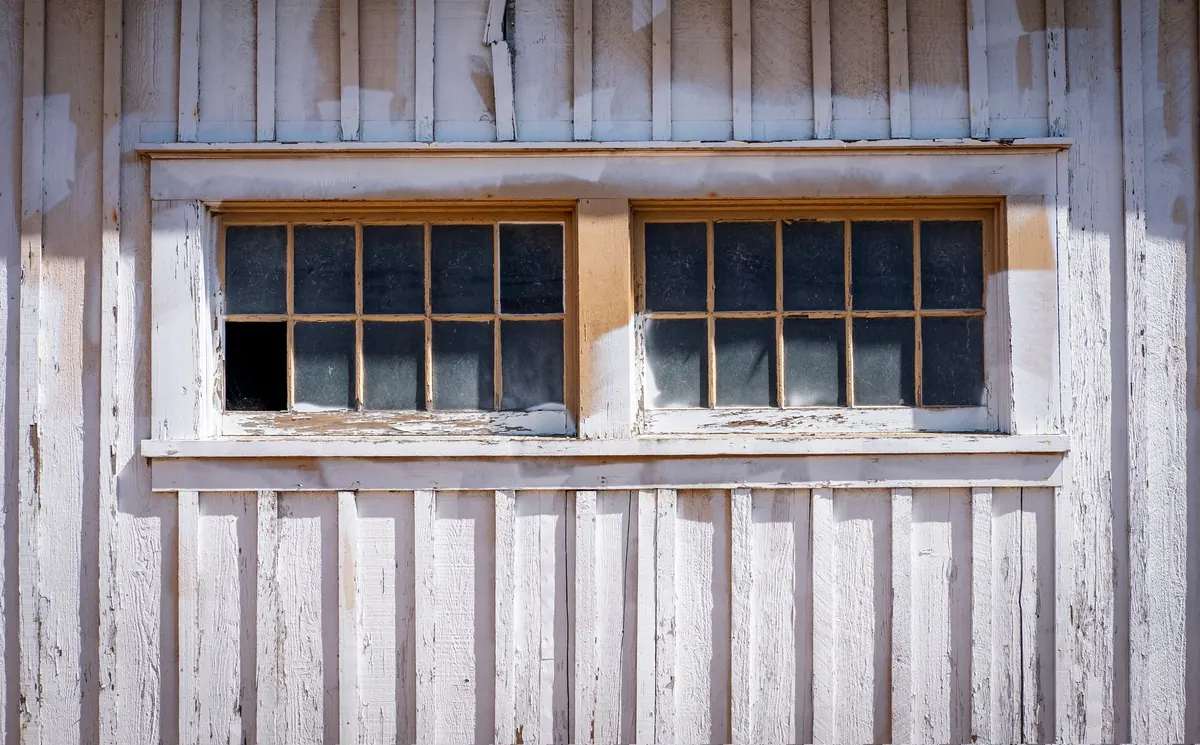 Old multi-pane sash windows in a weathered timber wall