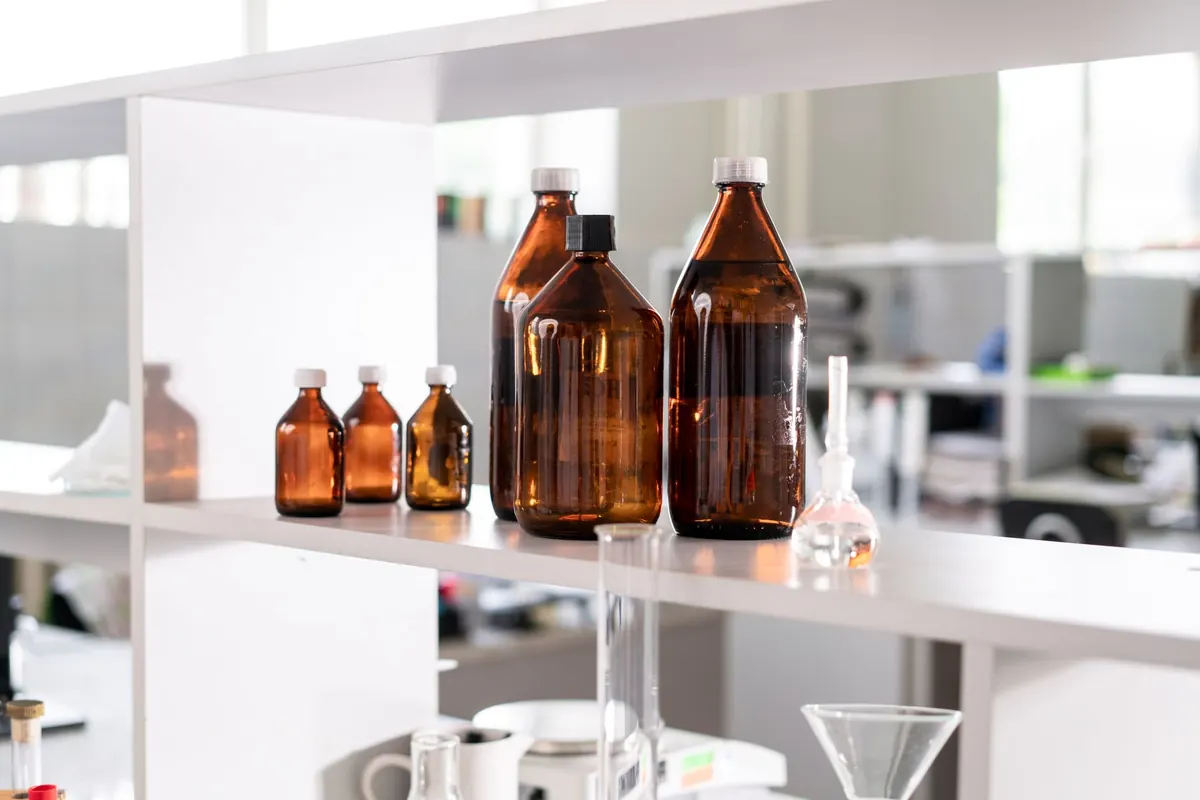 Amber and clear chemical bottles on a white shelf