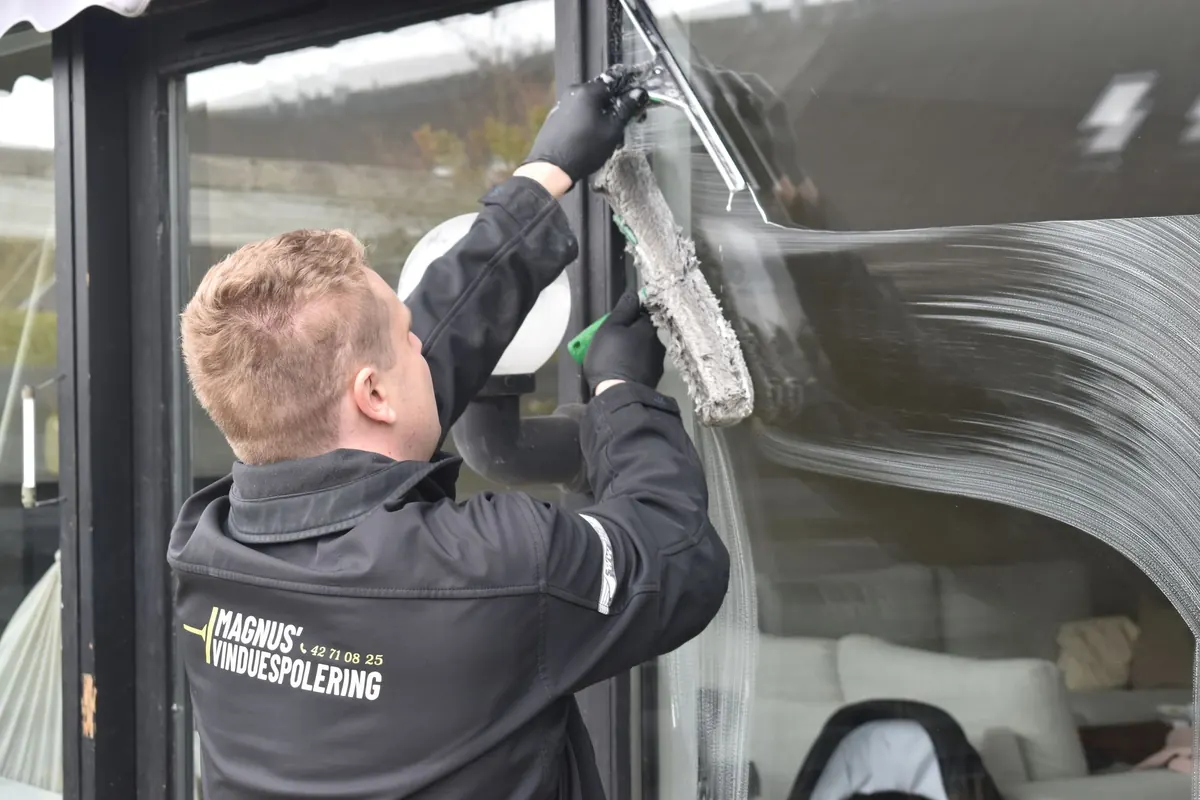 A window cleaner working a squeegee across a large pane